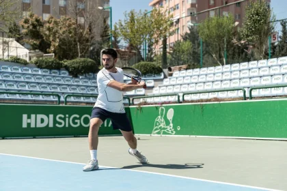 Giocatore di tennis in azione su cemento con racchetta e palla in volo