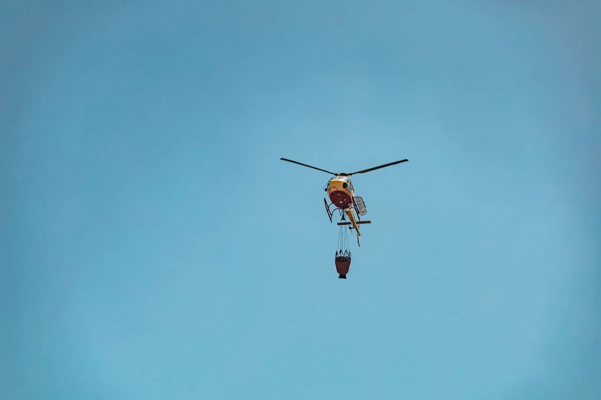 Elicottero antincendio in azione durante le operazioni di spegnimento di un vasto incendio boschivo