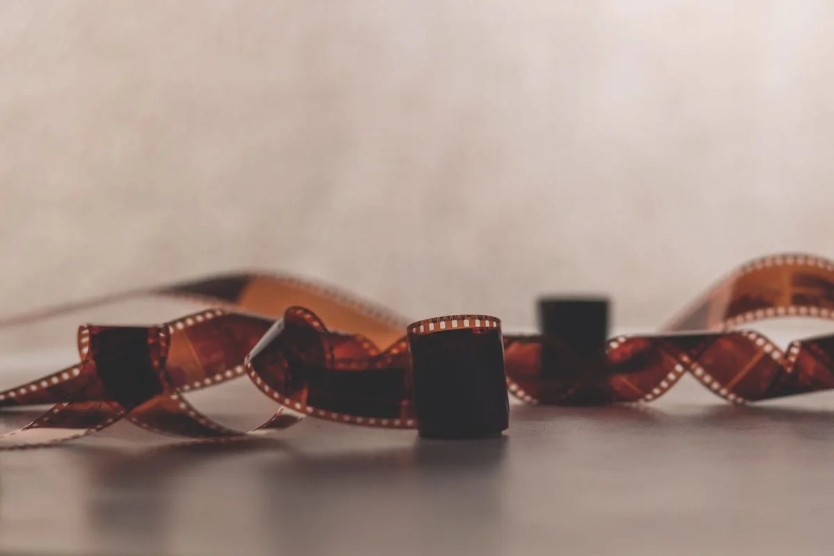 Bobina di film vintage e documenti di produzione su una scrivania in legno, simbolo del lascito del cinema italiano.