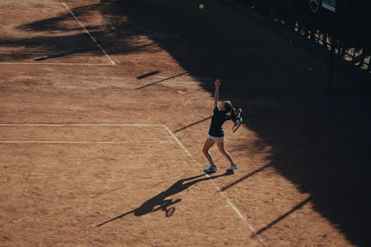 Tennista donna durante il servizio su campo in cemento