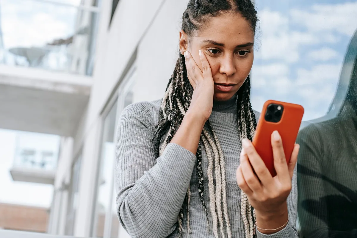 Giovane donna in spiaggia preoccupata per la privacy con smartphone nelle vicinanze