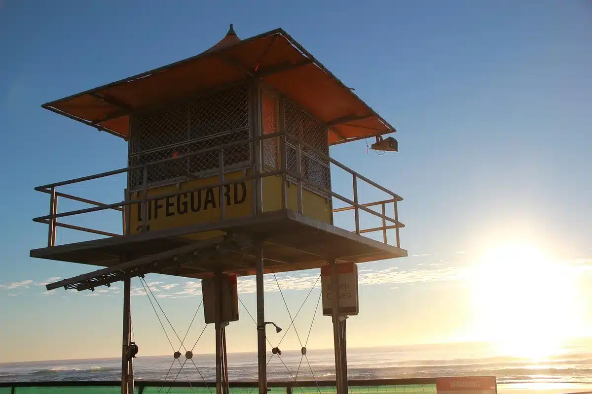 Close-up of anonymous lifeguard kit and a folded buoy on sand, nobody identifiable