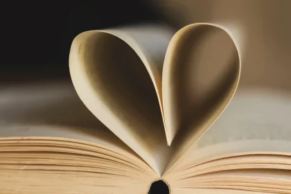 Un libro aperto illuminato da una lampada calda, con pagine ingiallite e le mani che tengono il libro delicatamente