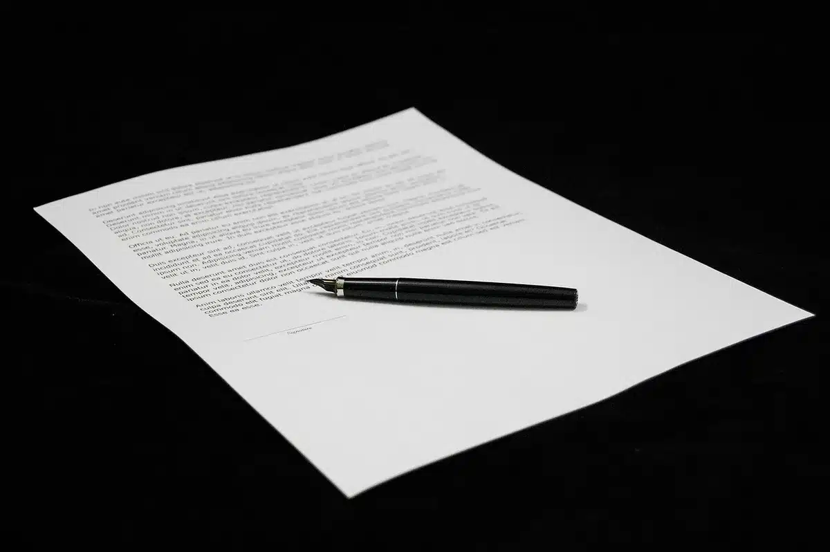 Close view of a simple stack of municipal agenda documents on a wooden desk, an anonymous pen beside them