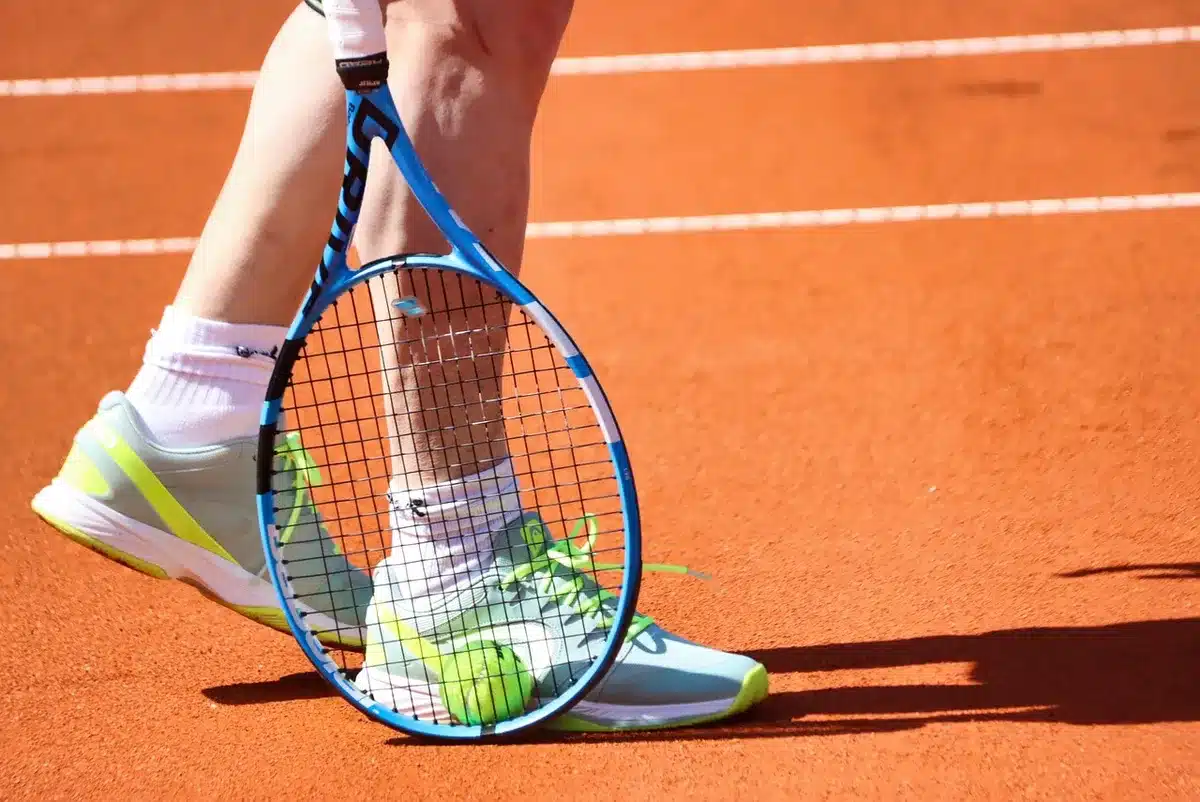 Silhouette di un giocatore su un campo da tennis con tabellone sfocato e spettatori in lontananza