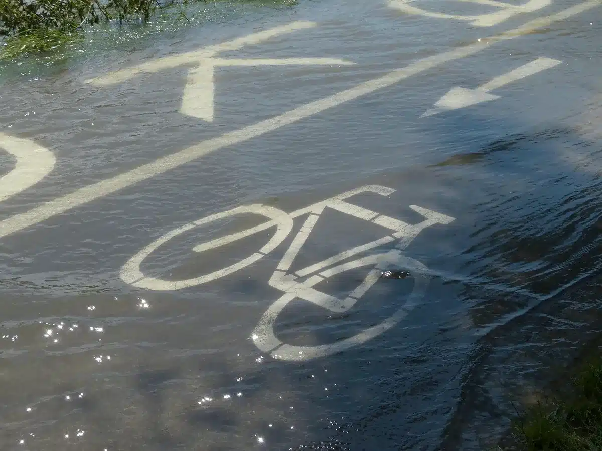 Evening shot of an illuminated unbranded cycle path with LED lamp posts lining the route, no people, wet pavement reflecting light