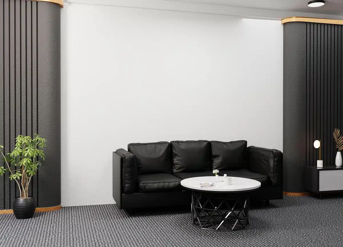 Empty waiting area with stacked brochures titled social services (unreadable), anonymous chairs and a wall noticeboard