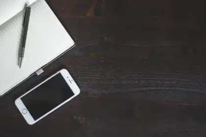 Mano anonima con libro e smartphone su tavolino in soggiorno, notifiche sfocate sullo schermo