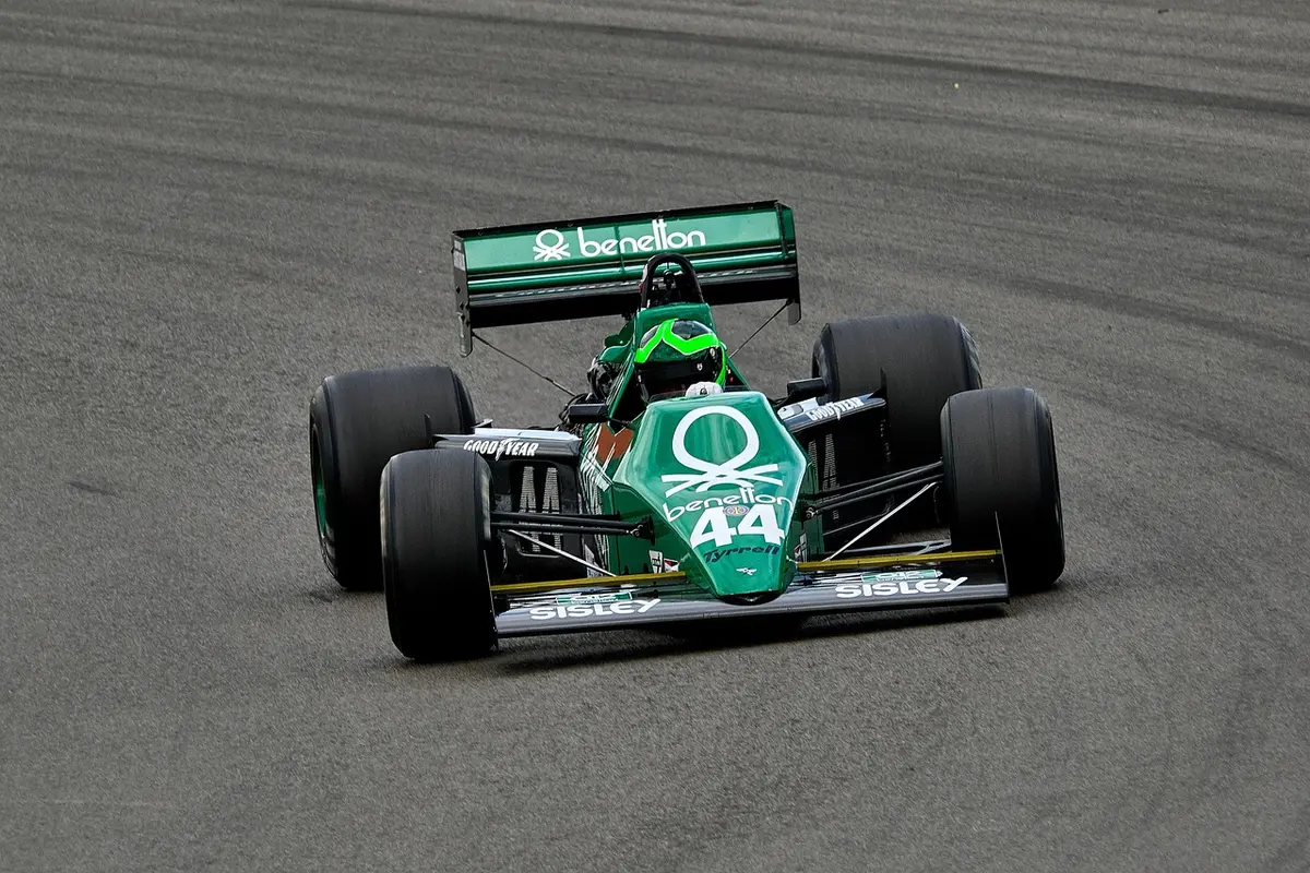 Meccanici e pilota di F1 in tuta anonima in garage moderno, concentrati su dati e strategie