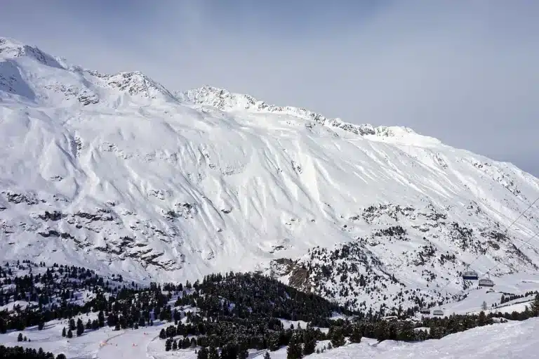 Pista da sci estiva vuota con roccia scoperta e neve residua alle Alpi