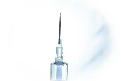 Siringa e fiala su un tavolo clinico con strumenti medici sfocati