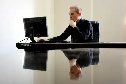 Silhouette walking away in a generic newsroom with unbranded monitor