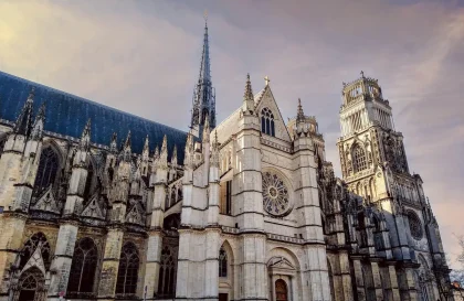 Gruppo anonimo di pellegrini vicino a un muro di pietra con fiori selvatici e candele