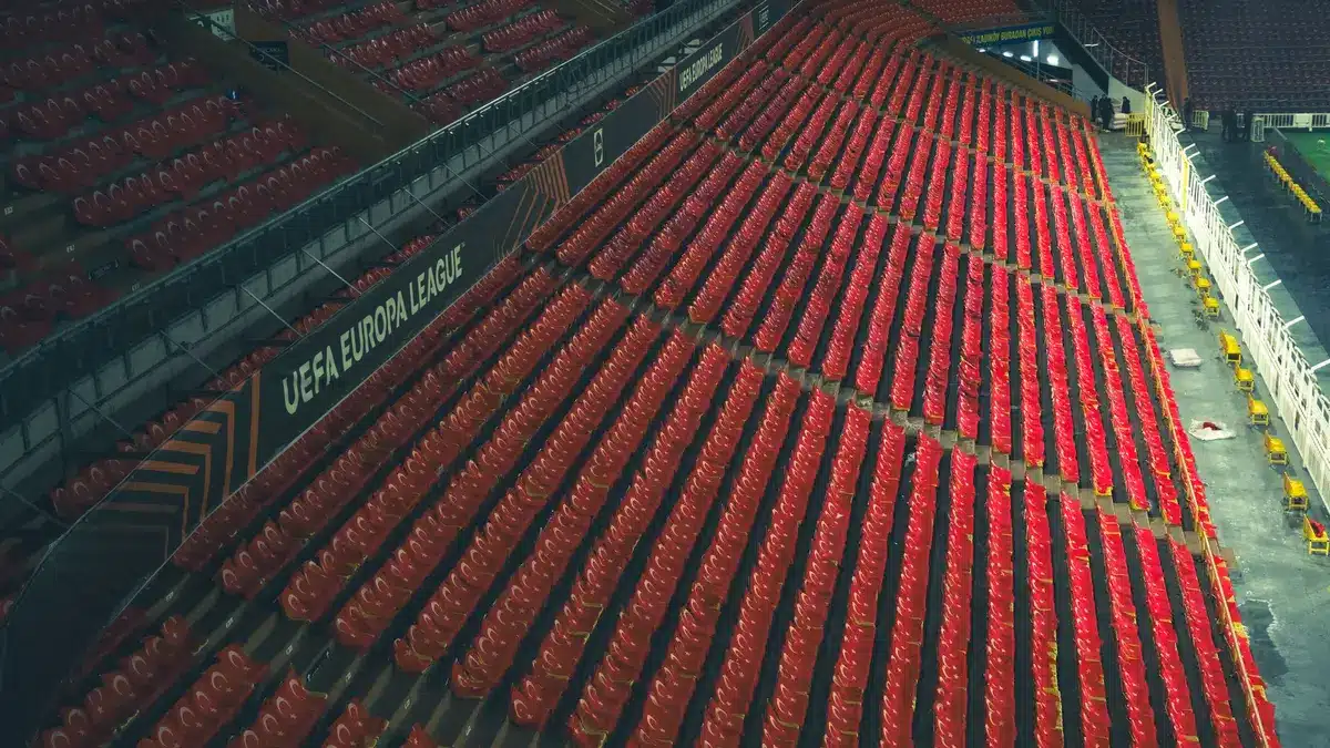 Empty stadium tunnel and a lone pair of boots left on the turf, dim floodlights and an abandoned match ball nearby