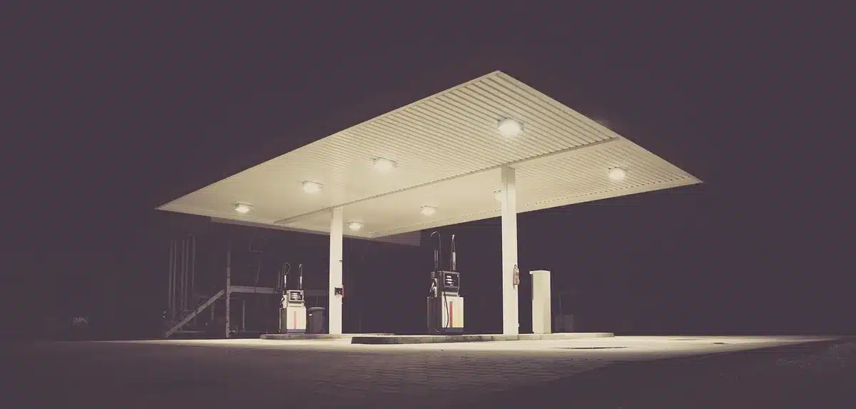 Empty regional ambulance parked by a closed petrol station, no people, a row of shuttered pumps and an anonymous medical bag visible inside the vehicle