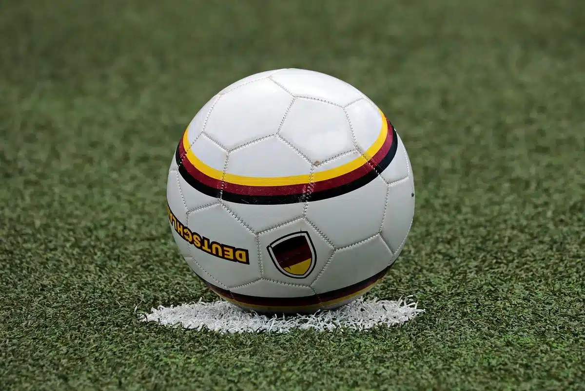 Anonymous pair of players' legs sprinting on wet turf toward the box, cleats kicking up droplets