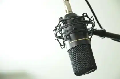Microfono vintage e spartiti su un tavolo in uno studio, sagome umane sullo sfondo