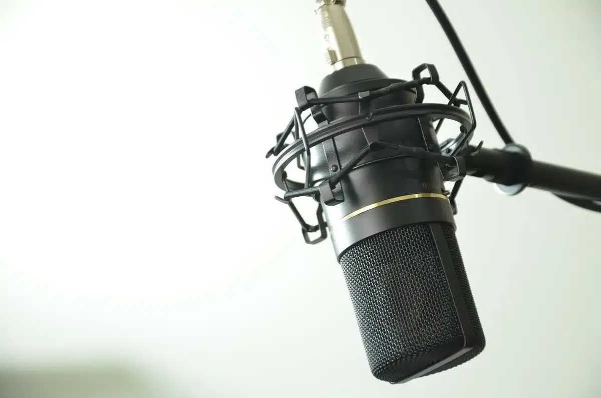 Microfono vintage e spartiti su un tavolo in uno studio, sagome umane sullo sfondo