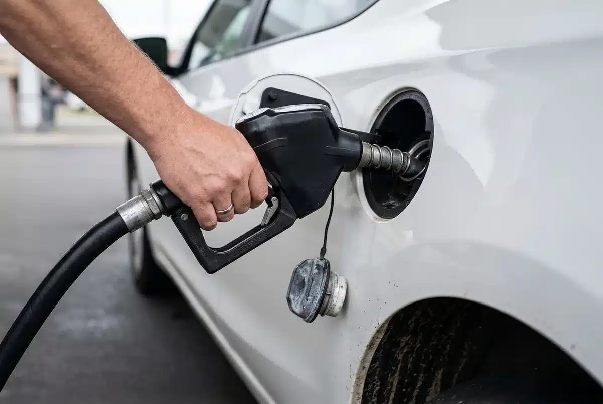 Pompa di benzina anonima con auto in fila, scena che evoca prezzi carburante