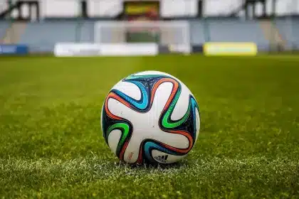 Corridoio dello stadio con palla da calcio e maglia appoggiata su una ringhiera, silhouette sullo sfondo