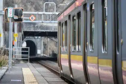 Sagoma di due persone sedute in un vagone, paesaggio diviso fuori dal finestrino