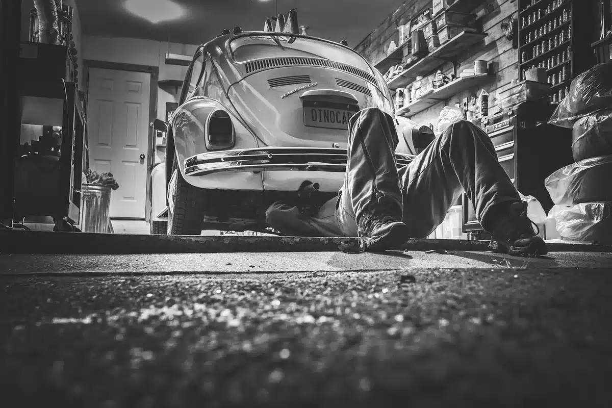 Mani di meccanici che tengono componenti della monoposto nel garage