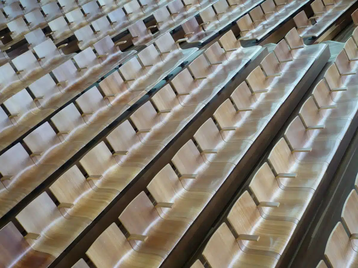 Empty auditorium stage with a single conductor's stand and sheet music on a music stand, warm stage lights glowing; evokes a concert night without showing people