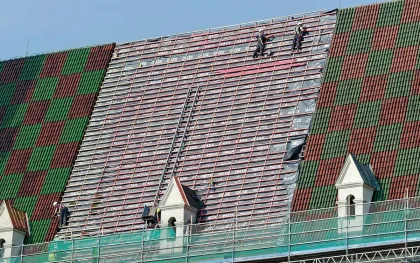 Palazzina con ponteggio e pannelli isolanti, operai anonimi al lavoro all'alba