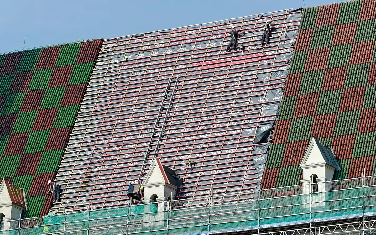 Palazzina con ponteggio e pannelli isolanti, operai anonimi al lavoro all'alba